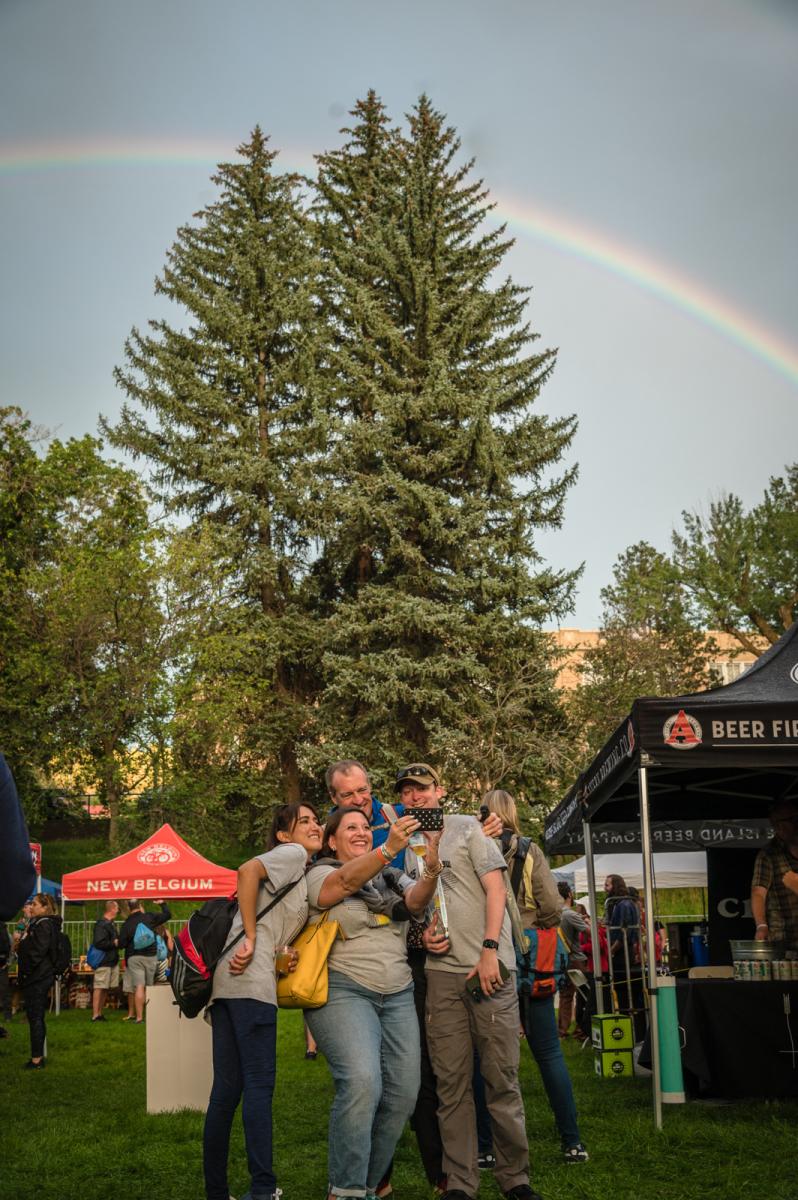 People taking a selfie in front of a rainbow at San Juan Brewfest